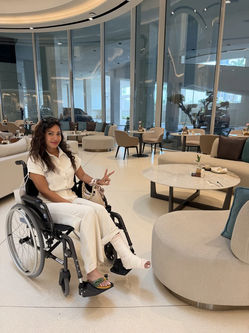 Ma femme en fauteuil roulant, la cheville plâtrée, dans le café vitré de l'hôpital
