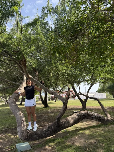 Mon épouse en tenue de tennis, assise sur un tronc d'arbre dans un parc