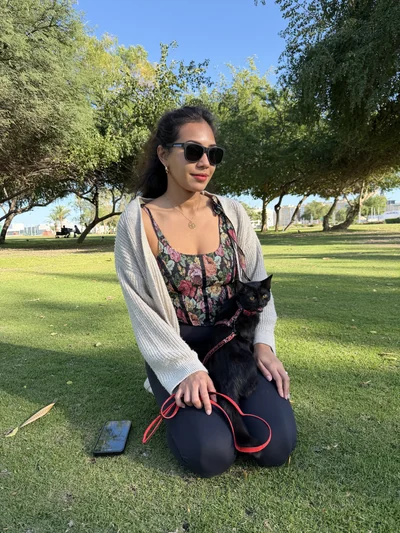 Mon épouse assise dans l'herbe d'un parc avec notre chat en laisse
