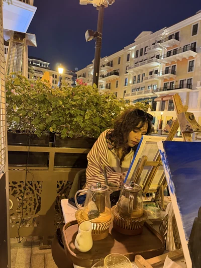 Mon épouse peignant en terrasse à la nuit tombée, immeubles éclairés au fond
