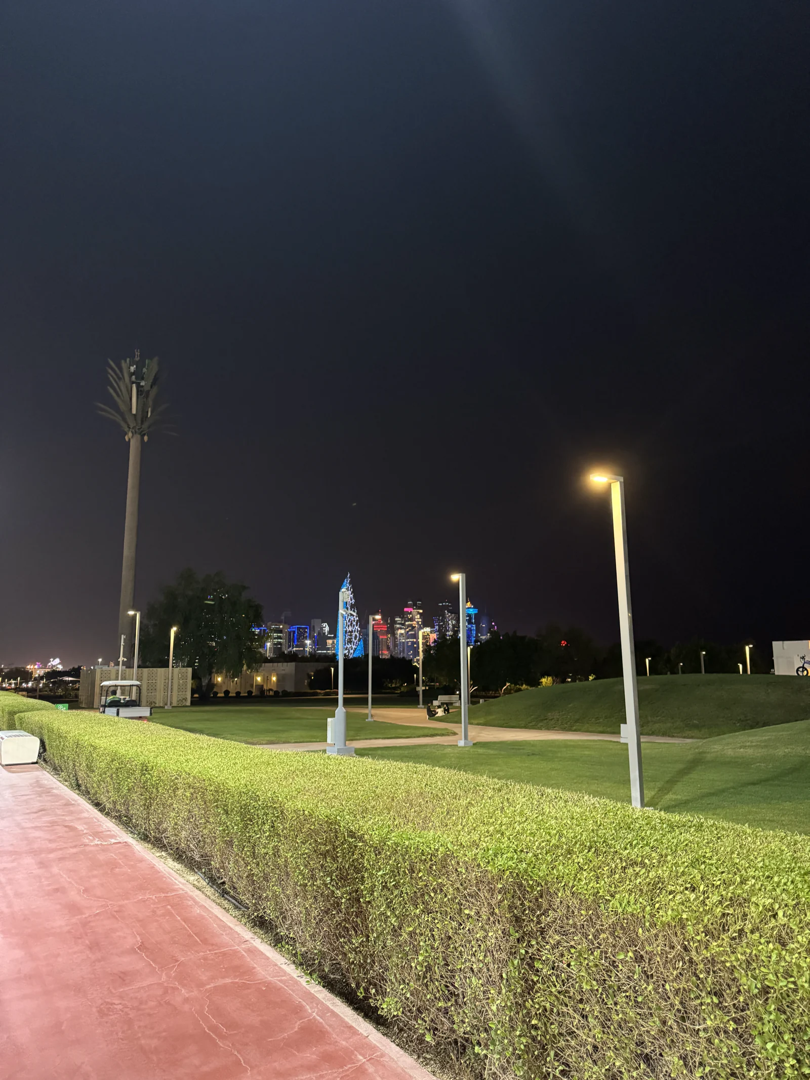 La piste de course rouge d'Al Bidda Park la nuit, la skyline de West Bay illuminée au fond