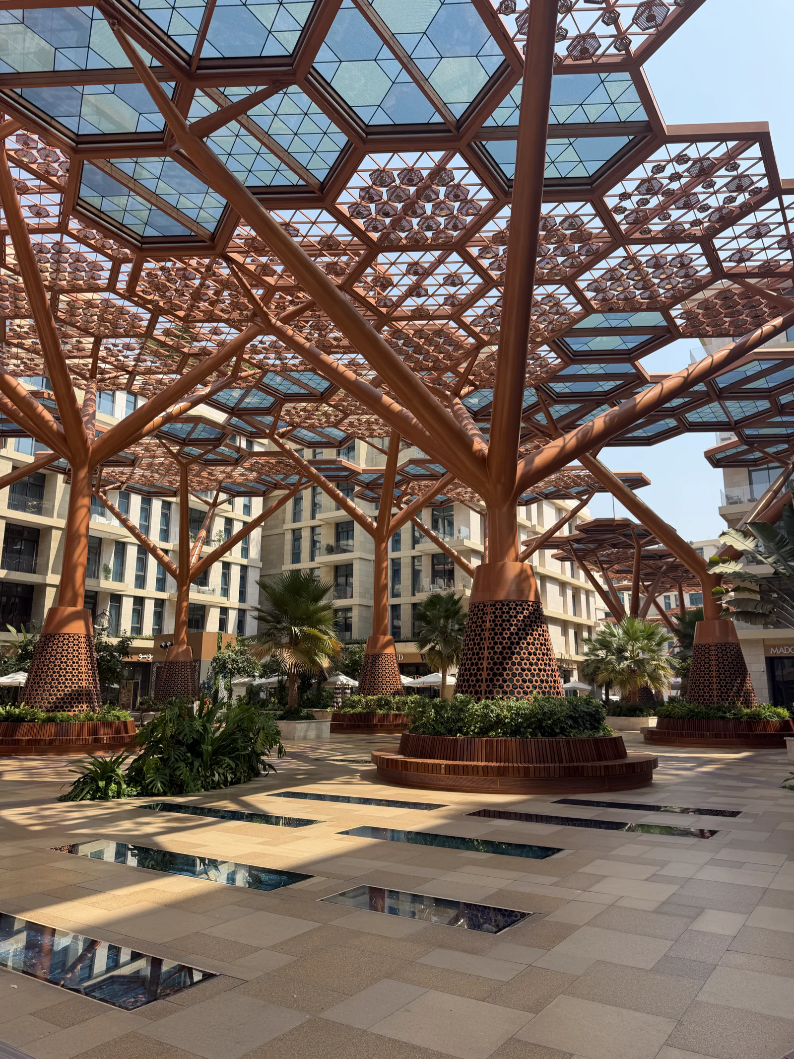 La promenade de Crystal Walk sous sa canopée d'arbres artificiels, palmiers et façades claires