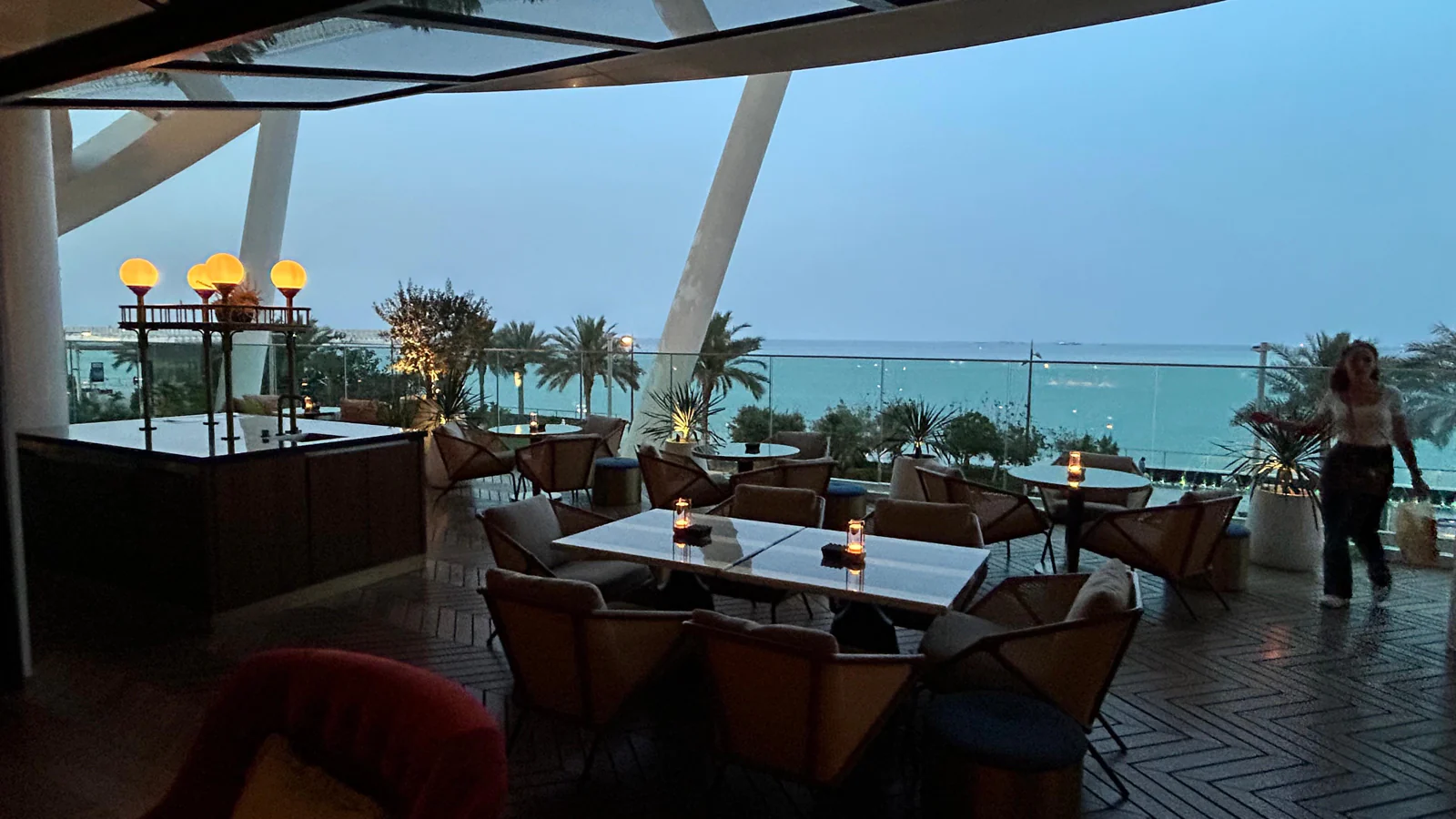 Terrasse de restaurant en bord d'eau à Lusail, tables dressées au crépuscule