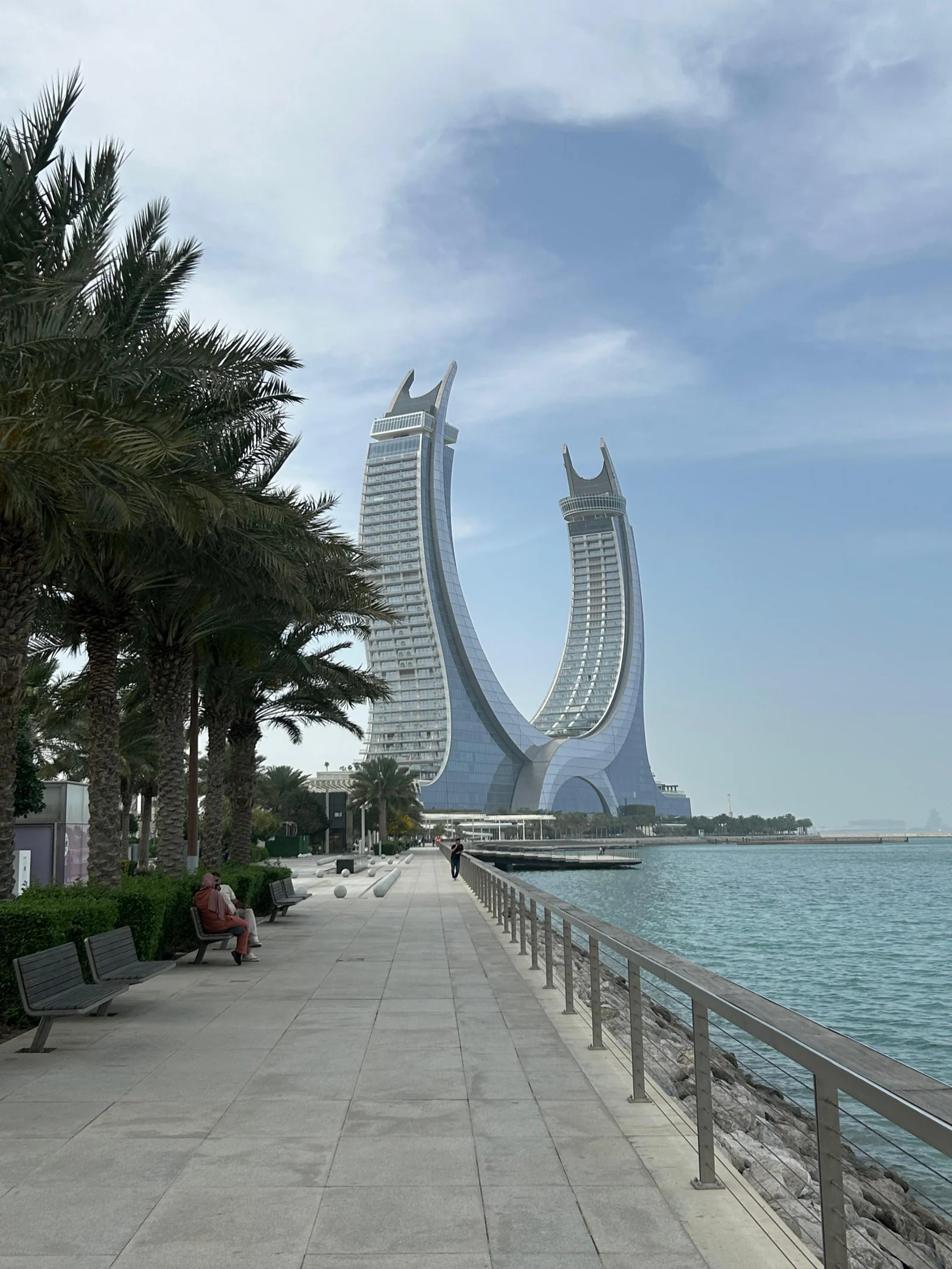 Promenade bordée de palmiers à Lusail, face aux tours en forme de croissant