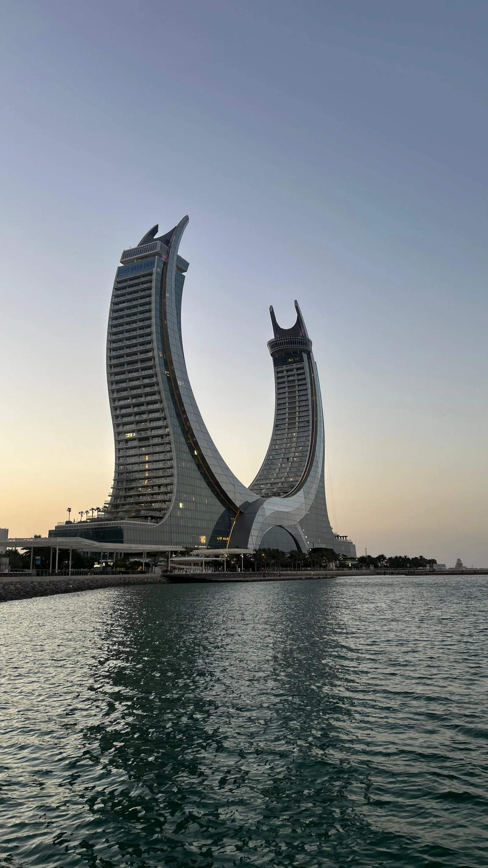 Les tours jumelles en forme de croissant de Lusail au coucher du soleil, reflétées dans l'eau