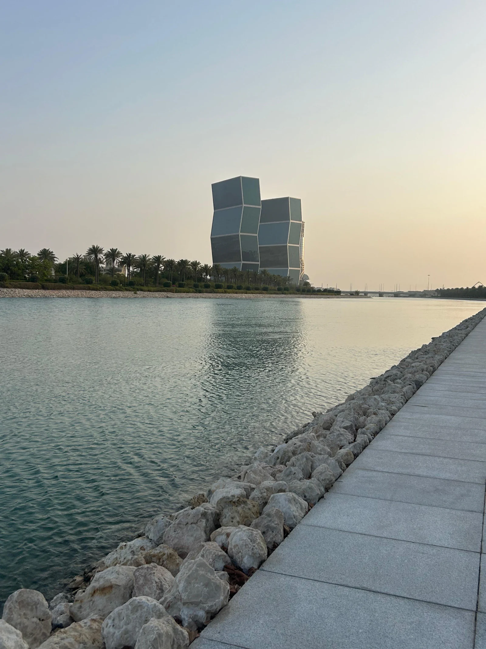 Digue de pierres et tour de Lusail au coucher du soleil, reflets sur l'eau