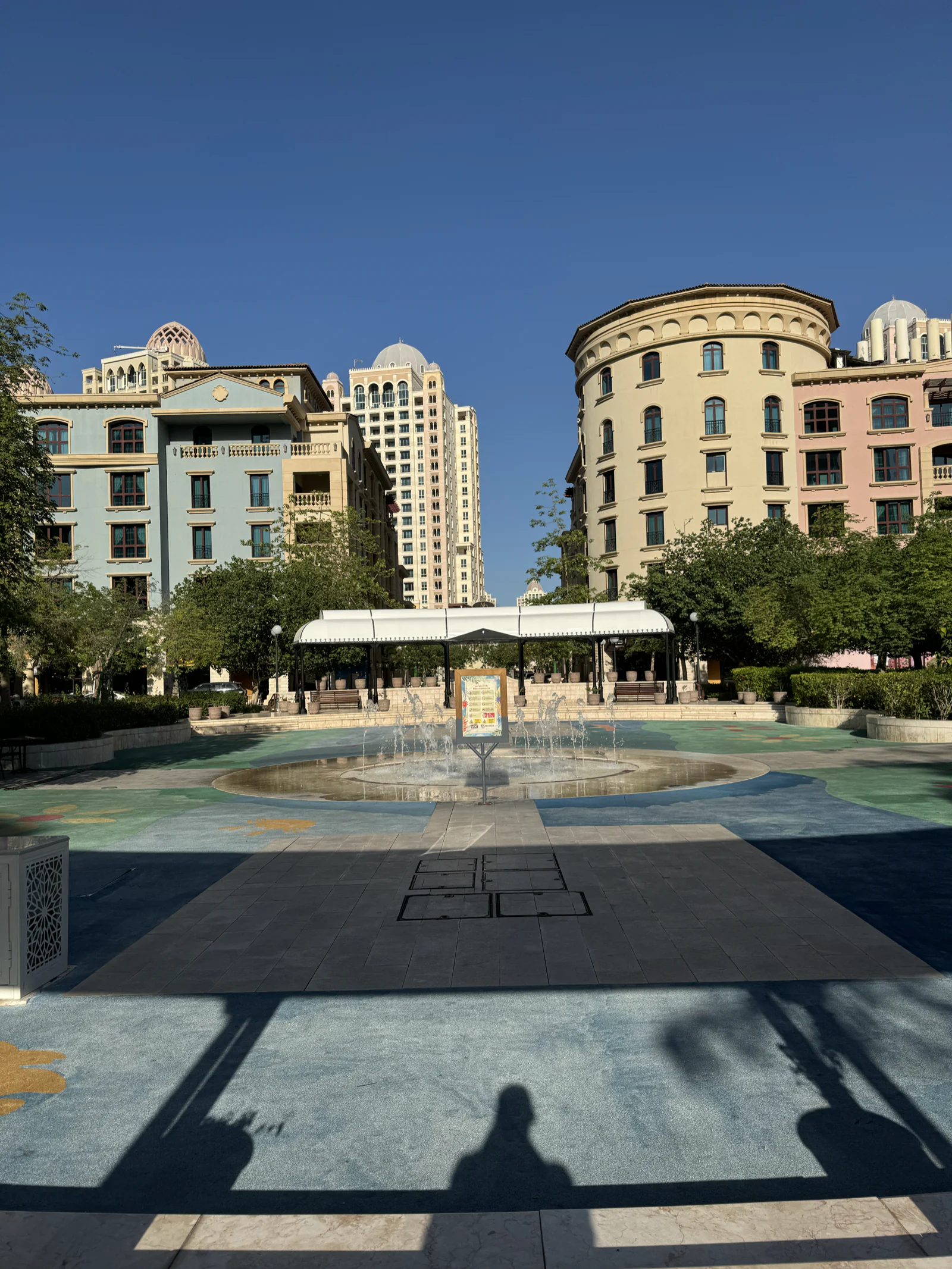 La place et sa fontaine au sol à Medina Centrale, immeubles pastel sous un ciel dégagé