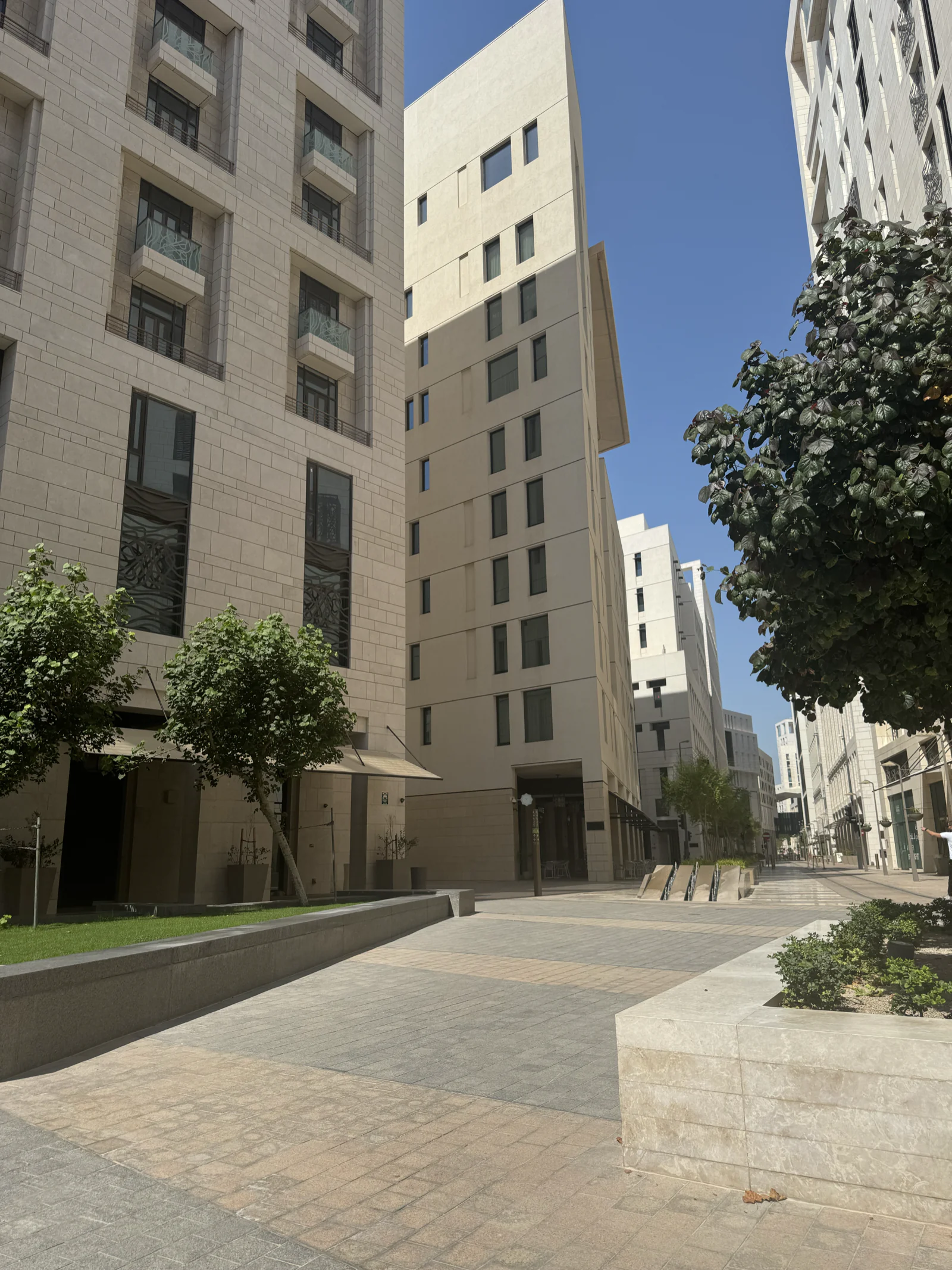 Rue résidentielle de Msheireb en plein jour, immeubles beiges et jeunes arbres