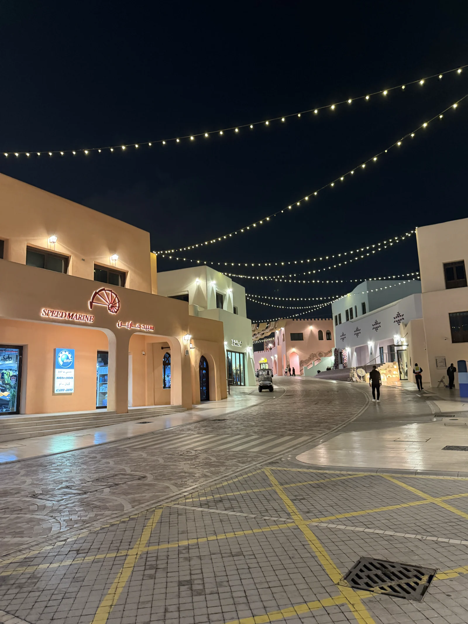 Rue piétonne du vieux port de Doha, éclairée par des guirlandes lumineuses en soirée