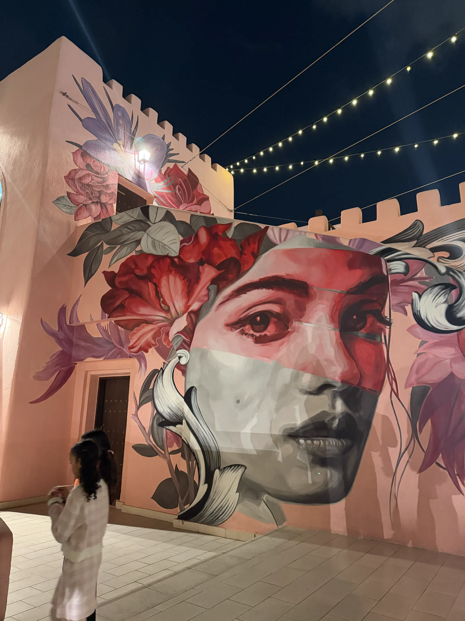 Fresque murale d'un visage de femme sur un mur du vieux port de Doha, à la tombée du jour