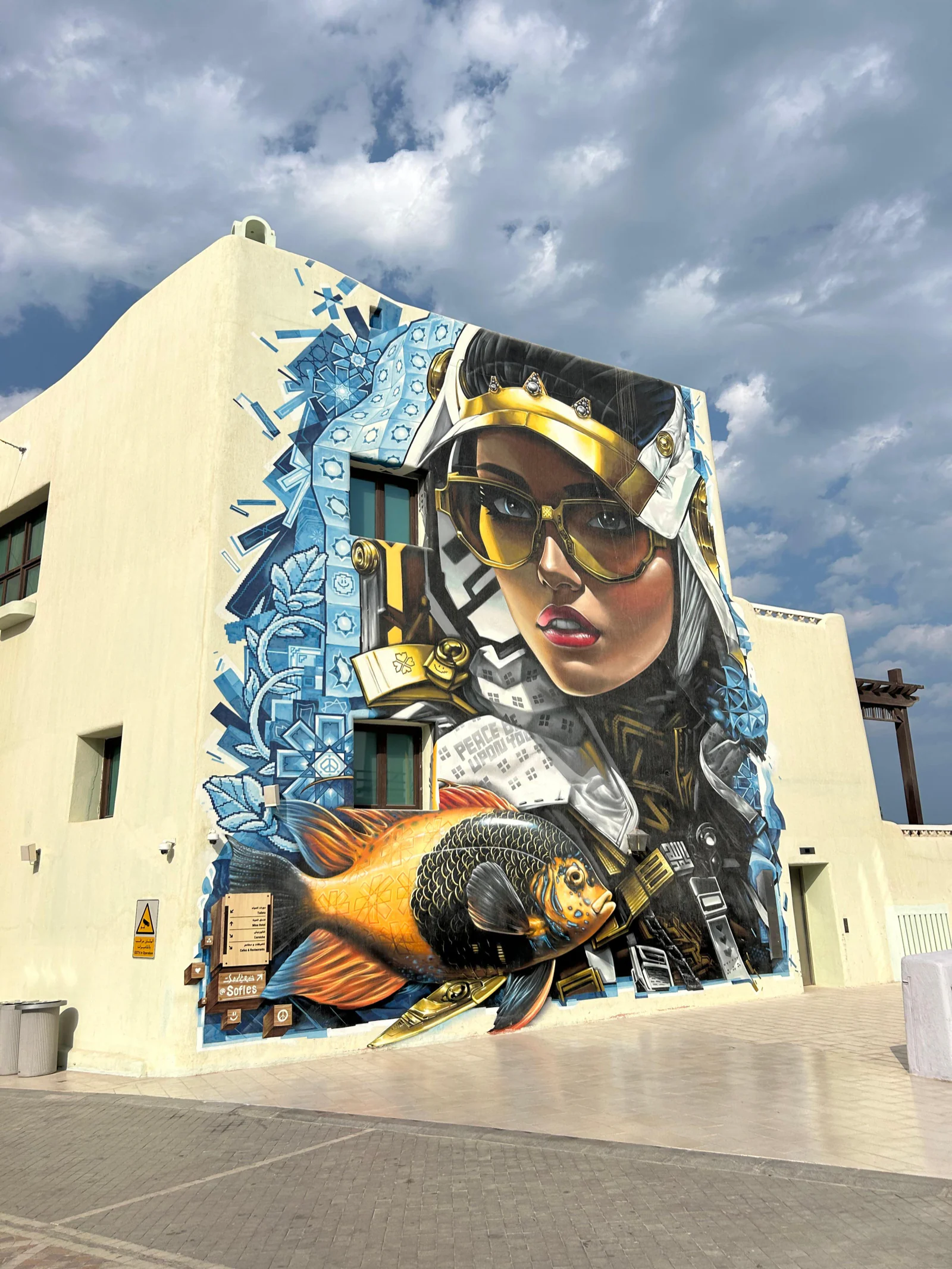 Grande fresque murale représentant une femme et des poissons sur une façade du vieux port de Doha
