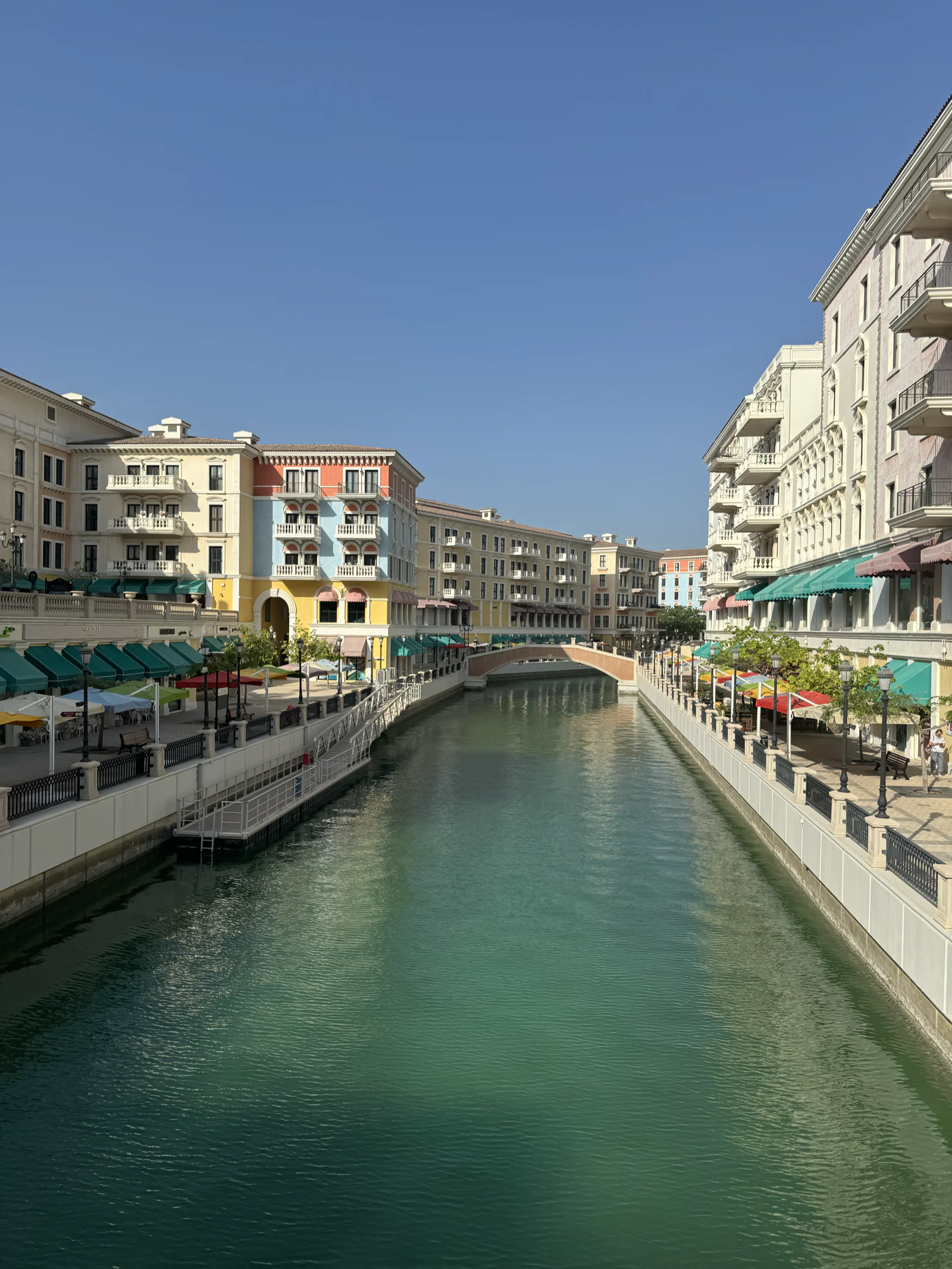 Le canal de Qanat Quartier à The Pearl en plein jour, façades colorées et pont de pierre