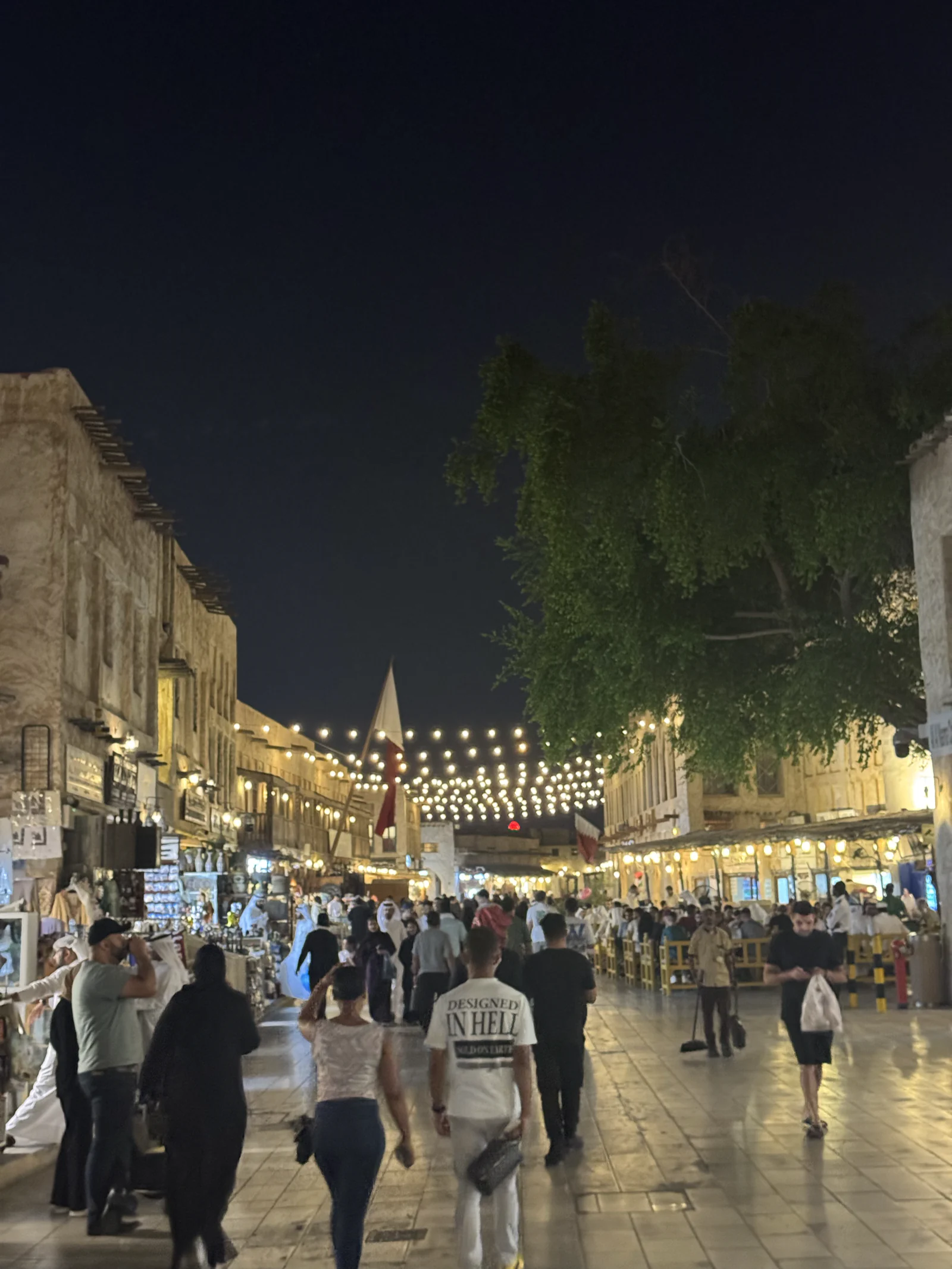 L'allée principale du souq Waqif la nuit, guirlandes lumineuses au-dessus des promeneurs et boutiques éclairées