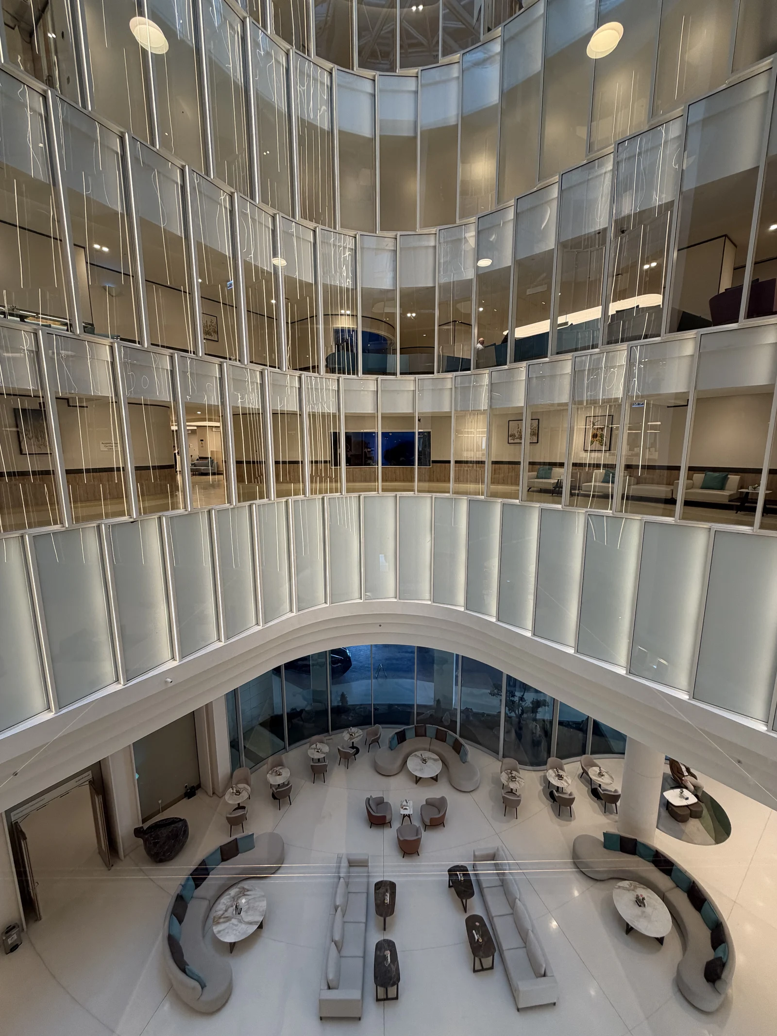 L'atrium vu d'en haut, coursives vitrées sur plusieurs étages et salon d'attente en contrebas